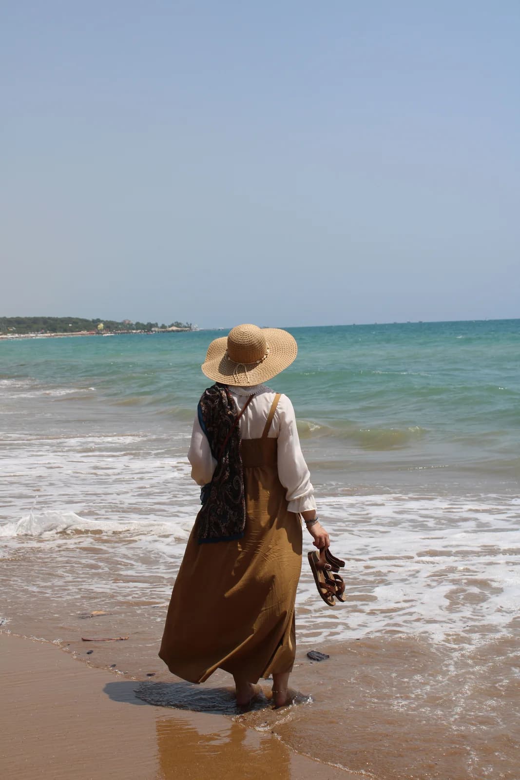 Woman in an easy summer outfit walking beside the sea